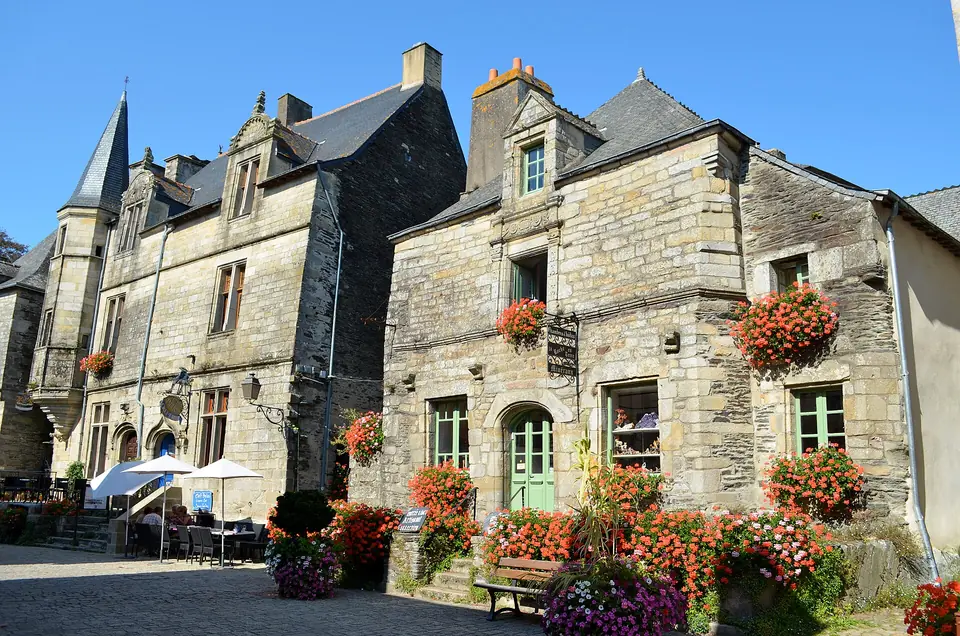 Maisons en granit fleuries de Rochefort-en-Terre, dont une à tourelle en encorbellement, sous des toits d'ardoise.